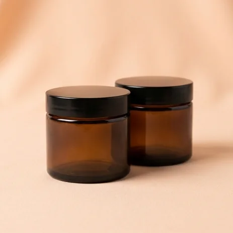 Two amber glass jars on a peach backdrop