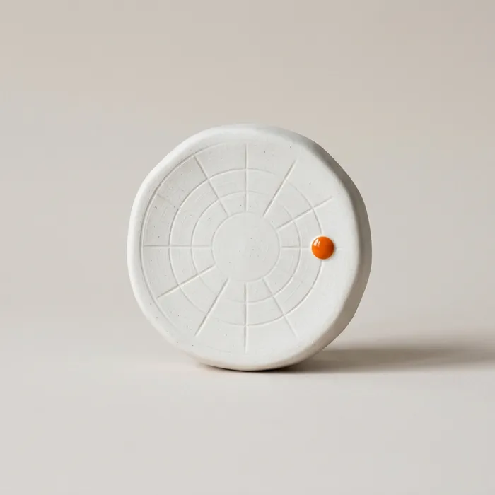 A white ceramic dial object on a pale background