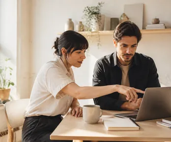 Two Sparkstack colleagues reviewing a page draft on a laptop