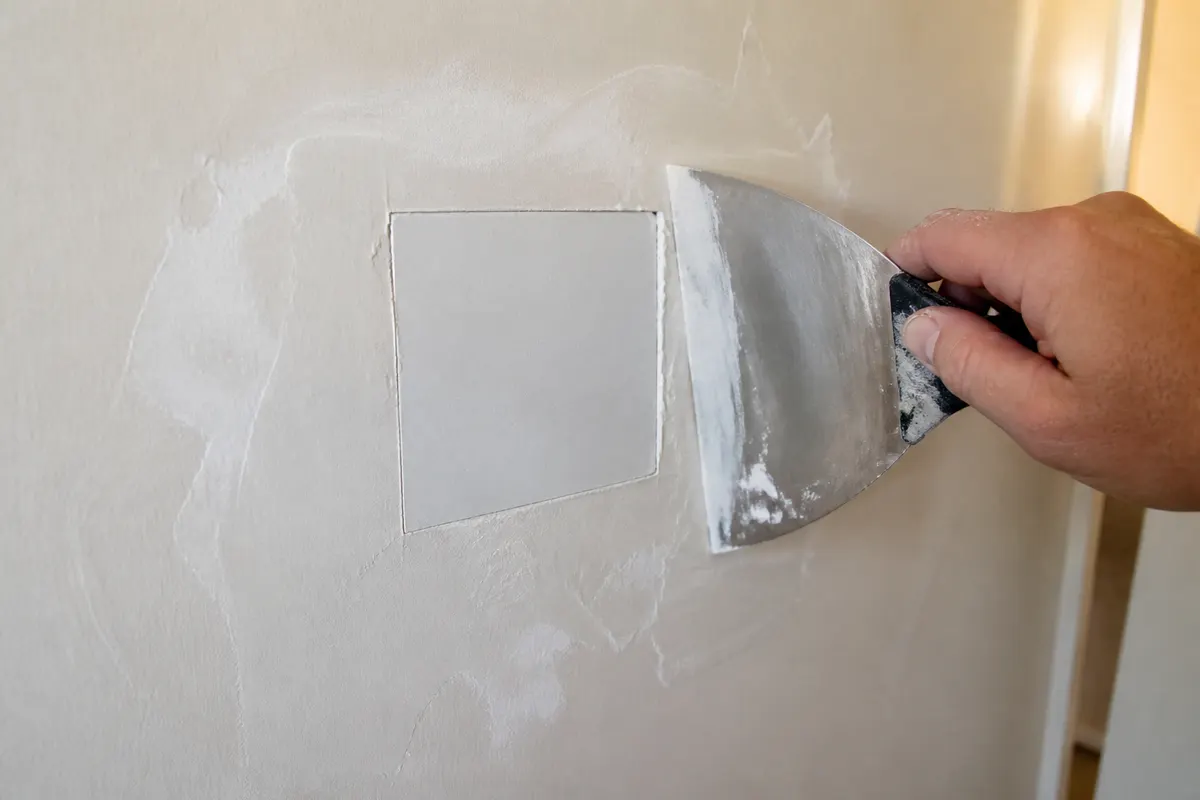 Square drywall patch with feathered joint compound and a taping knife