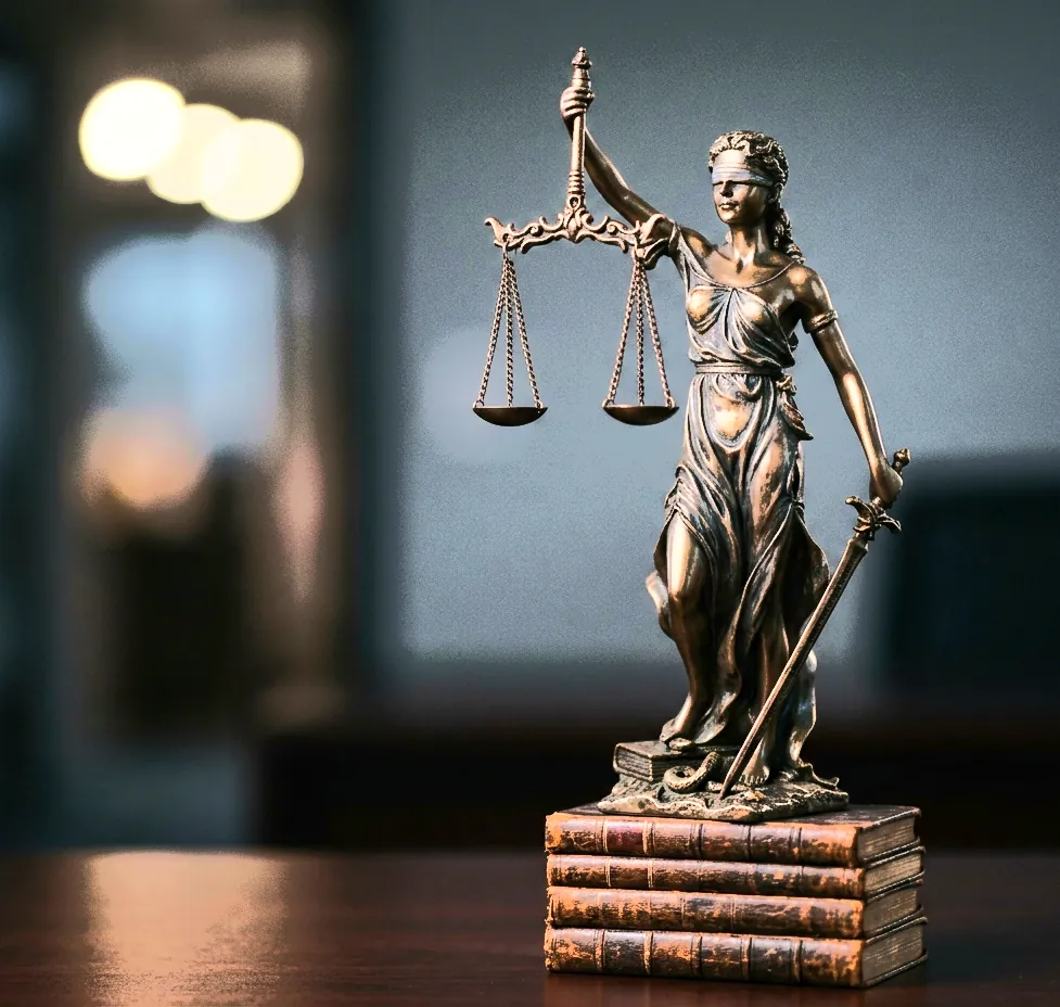 Blindfolded bronze statue holding balance scales on a stack of old books