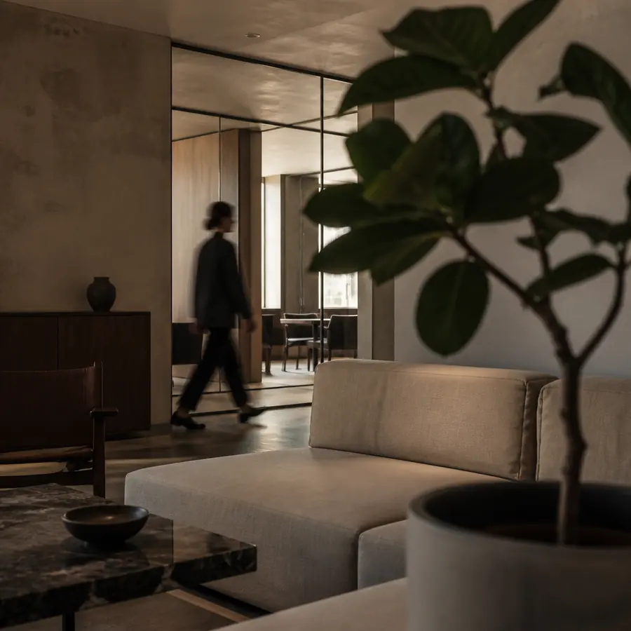 Office lounge with a person walking past a glass partition