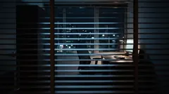 A dark office at night seen through half-closed window blinds