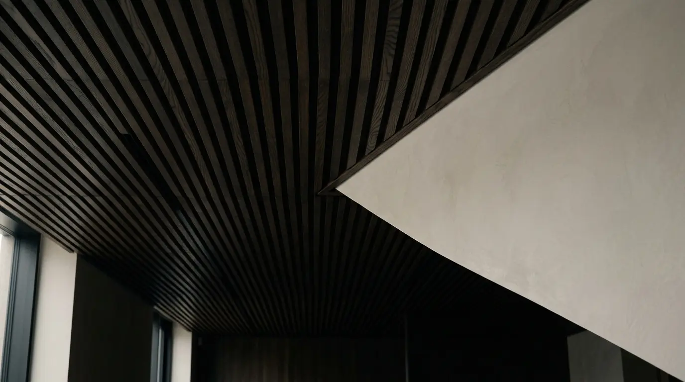 Abstract architectural detail of a dark slatted ceiling against a pale wall