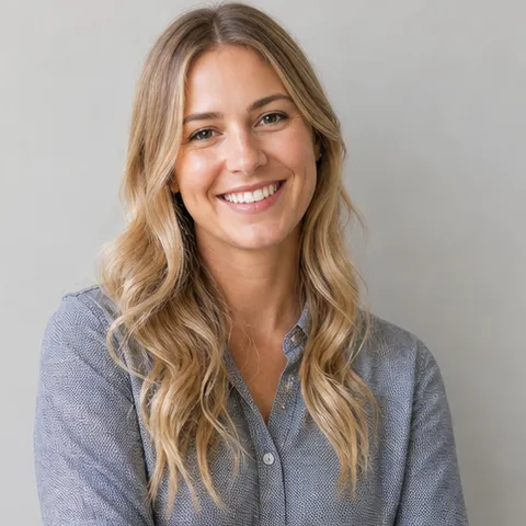 Smiling woman with wavy blond hair in a grey patterned shirt
