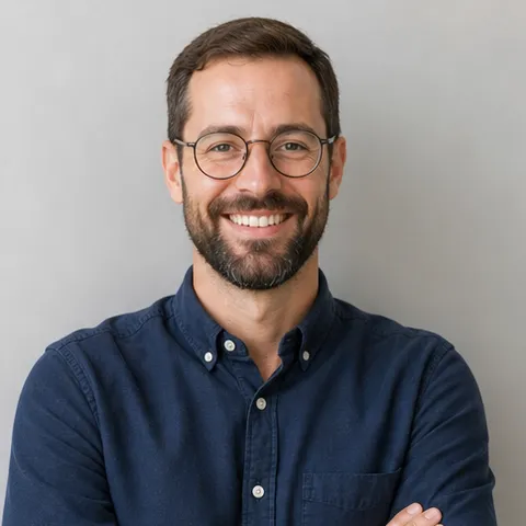 Smiling bearded man with round glasses in a navy shirt