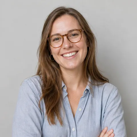 Smiling woman with glasses and light brown hair, arms folded