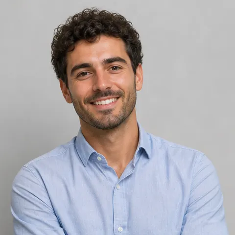 Smiling man with dark curly hair in a light blue shirt