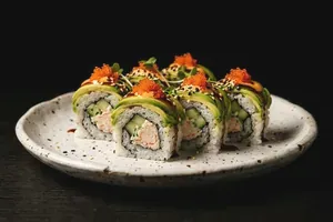 A cut roll topped with avocado on a round speckled plate