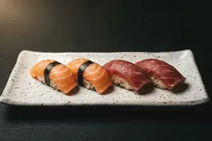 Two pieces of pressed nigiri on a pale speckled plate