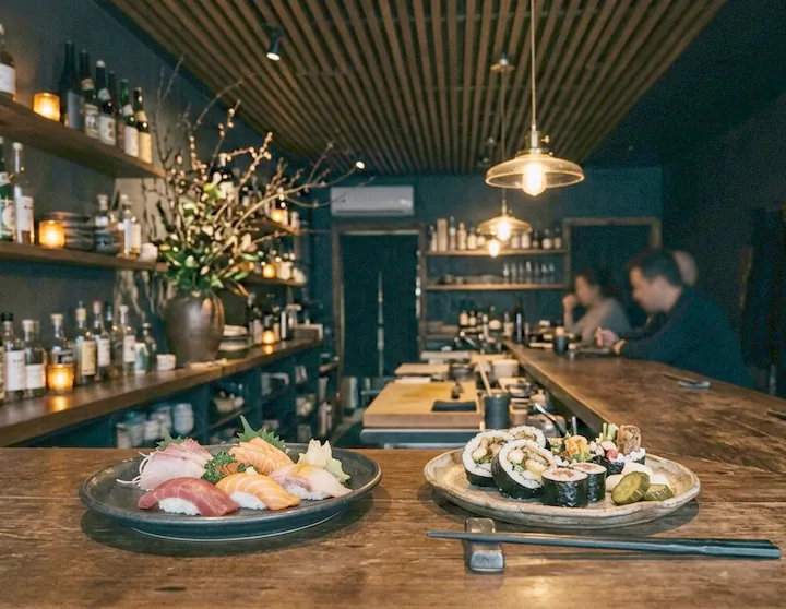 The dim counter room with bottles on the back shelves and warm pendants