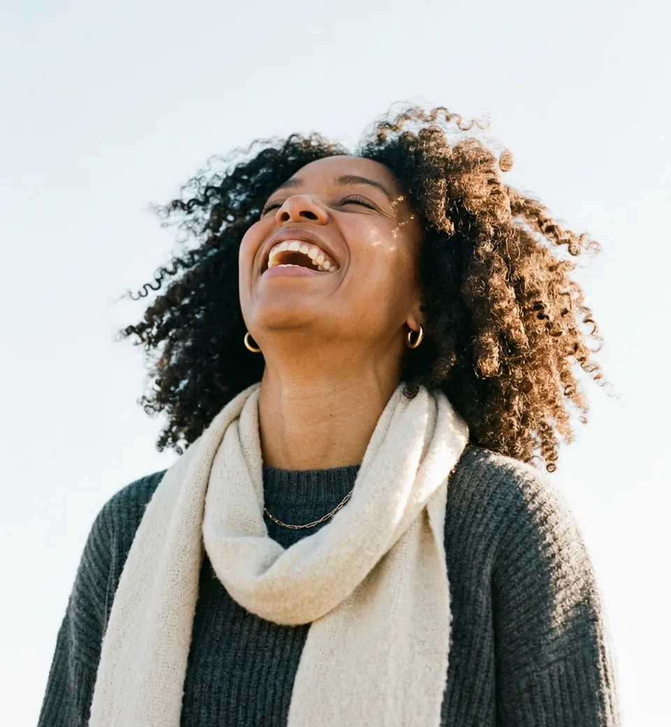 A laughing woman outdoors against a pale sky