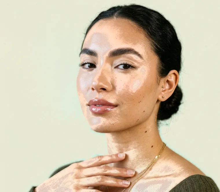 Client with fine gold chains, one hand raised toward her collarbone after a facial