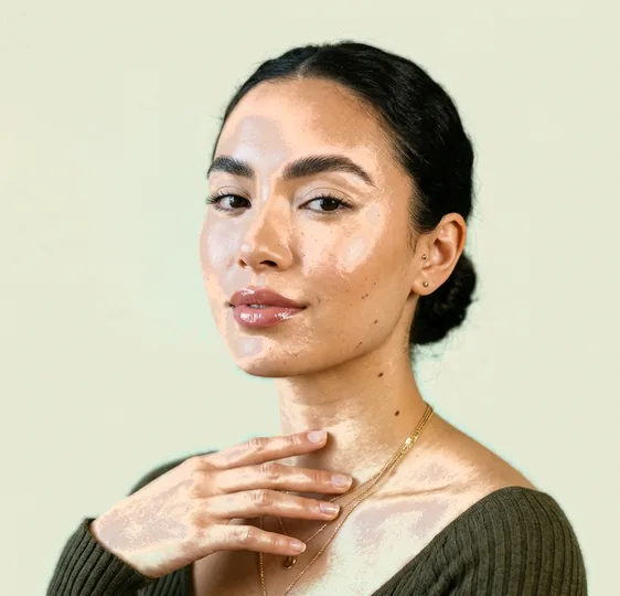 Client with fine gold chains raising one hand toward her collarbone