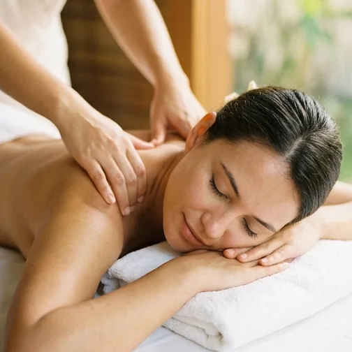 A therapist pressing gently on a relaxed guest's shoulders