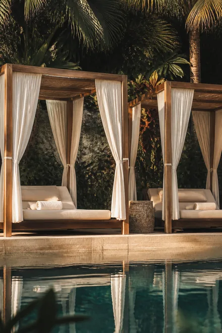 Cabana beds with white curtains beside the pool.