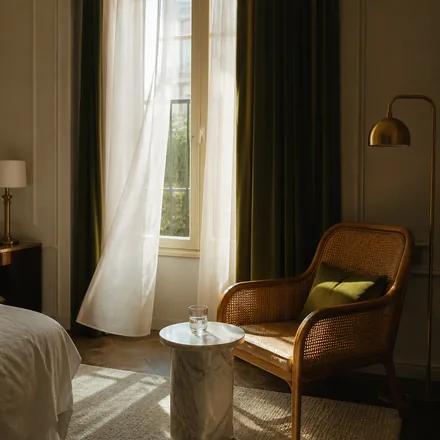 A bright room corner with gauzy drapes, a rattan chair and a marble side table.