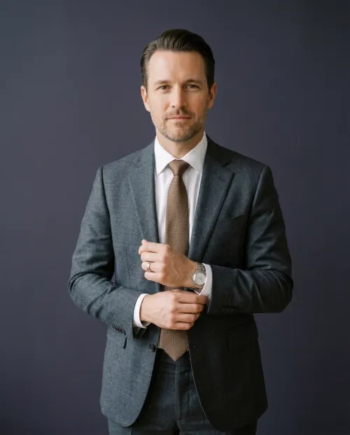 Julian Pruitt adjusting his shirt cuff in a charcoal suit