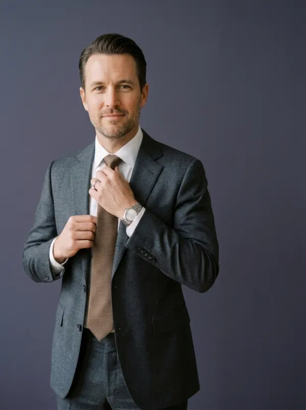 Julian Pruitt, a Charlotte business attorney, adjusting his tie in a charcoal suit