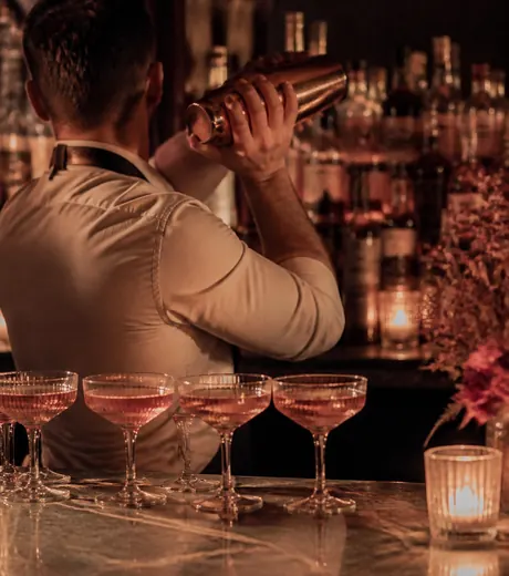 A bartender shaking a drink behind the marble counter