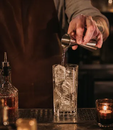 A clear drink poured over ice at the bar