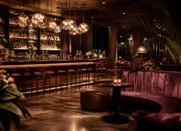 The long bar at the back of the dining room, lit by hanging glass globes