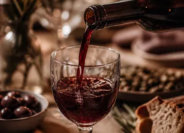 Red wine poured into a small glass at a laid table