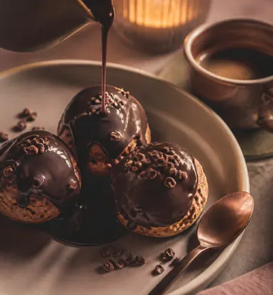 Three small chocolate puddings under a poured sauce
