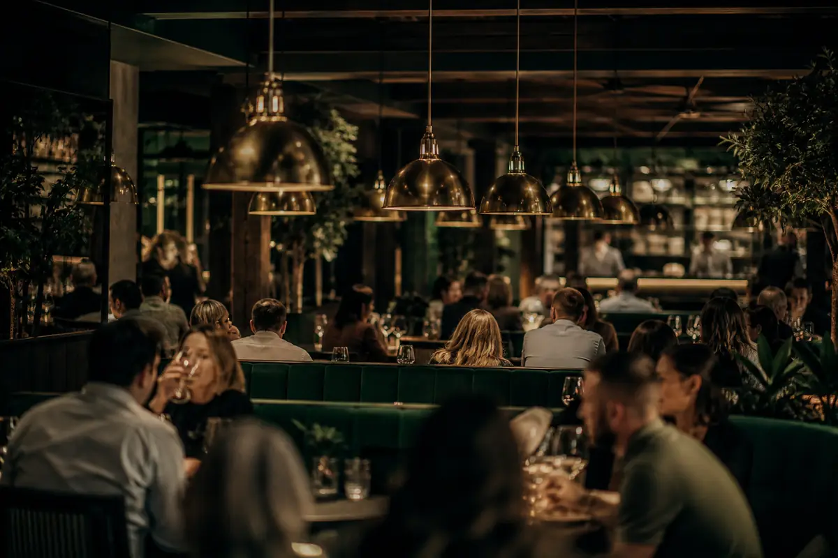 Wide view of a full dining room under rows of warm pendant lamps